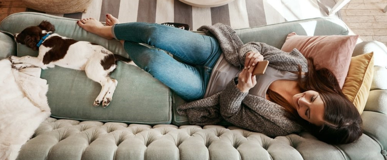 Girl & dog on couch, girl holding mobile phone